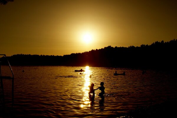 Les gens se baignent sur fond de coucher de soleil