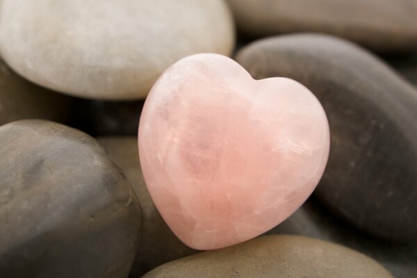 Coeur de pierre rose parmi les pierres ordinaires