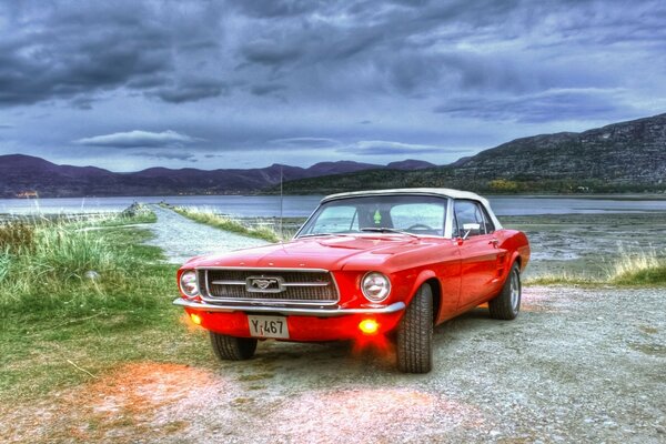Mustang rouge près du lac par temps nuageux