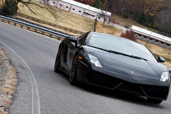 Lamborghini noir chevauche la route avec des bosses sur les bords sur un fond de paysage rustique d automne