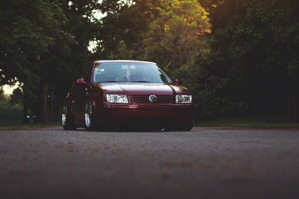 Volkswagen Jetta couleur cerise sur la route dans la forêt