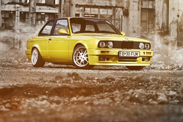 Jaune discret BMW série 3 E30 sur fond de ruines