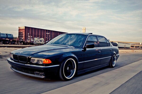 Une bmw 740i bleue sur le chemin de la gare