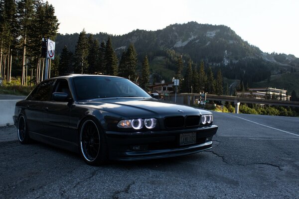 BMW noir sur la route sur fond de montagnes