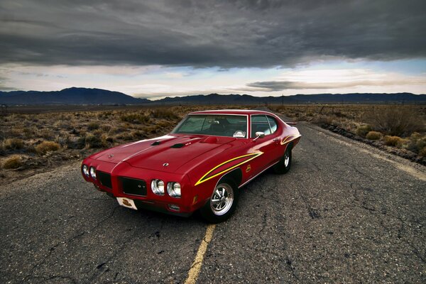 Une voiture rouge Pontiac fait demi-tour sur la route