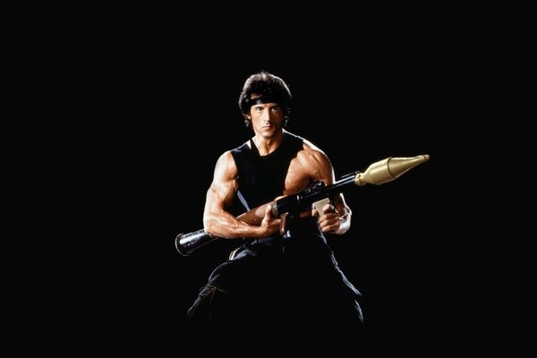Sylvester Stallone dans le rôle de Rimbaud sur fond noir avec des armes