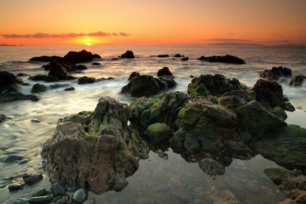 Pierres au bord de la mer sur fond de coucher de soleil