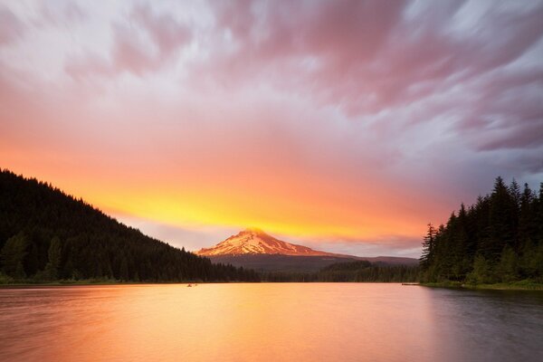 Lac au coucher du soleil et les montagnes dans les nuages