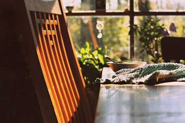 Chaise en bois à côté de la table sur laquelle le petit déjeuner est servi sous le soleil levant