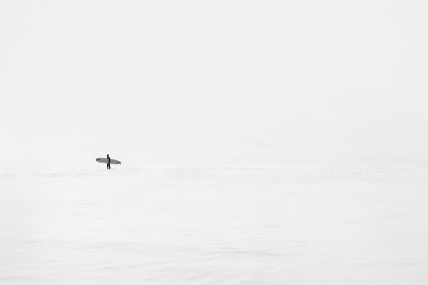 Homme avec planche dans la mer claire