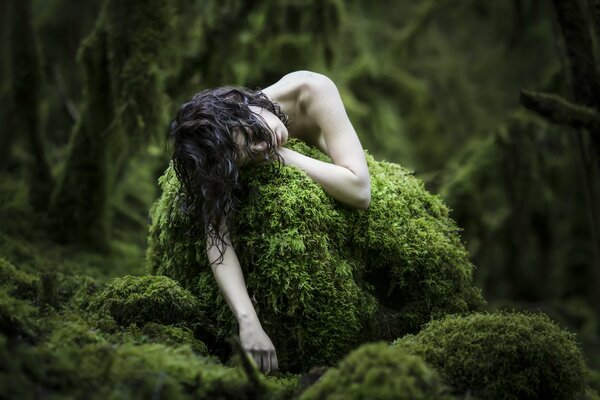 Pâle de la jeune fille dans la forêt sur la mousse
