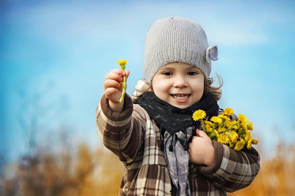 Fille avec un bouquet de premiers pissenlits