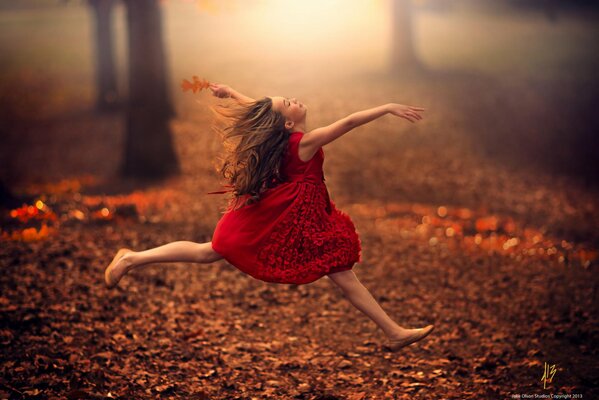 Fille en cours d exécution dans une robe rouge sur les feuilles