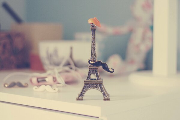 La petite tour eiffel sur la table dans le chapeau et la moustache