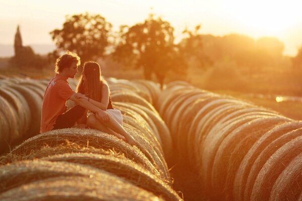Couple sur une botte de foin au coucher du soleil