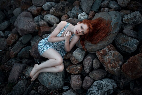 Fille rousse avec des taches de rousseur se trouve sur la pierre froide