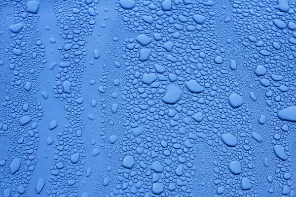 Gouttes de différentes tailles sur la surface bleue