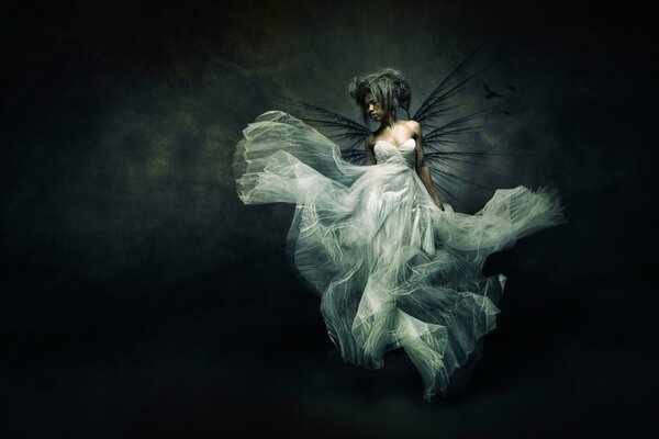 Fille avec des ailes pendantes en robe de demoiselle d honneur sur fond noir