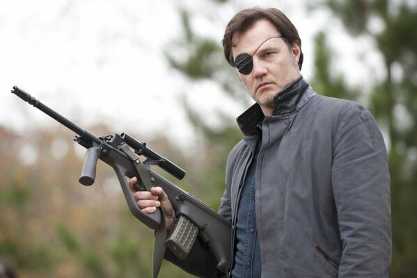David Morissey dans un bandeau sur un œil et un fusil de chasse