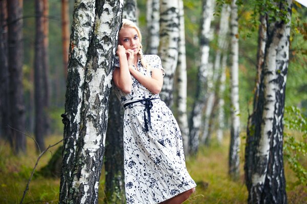 Belle fille blonde se pencha sur le bouleau
