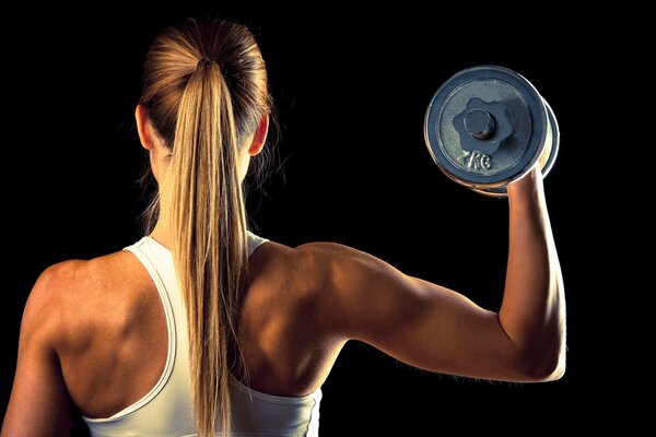 Fille athlète avec des haltères 2 kilogrammes