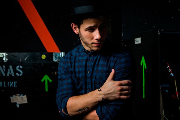 Nick Jonas se serre les bras et regarde à gauche