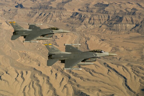 Deux F-16 Fighting falcon volent sur fond de désert