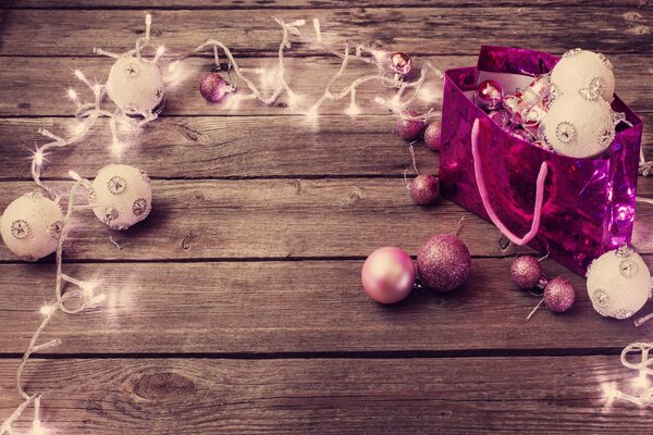 Guirlande de Noël rose avec des boules lumineuses sur un plancher en bois