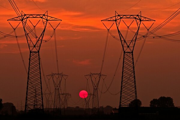 Silhouettes de supports de lignes électriques au coucher du soleil
