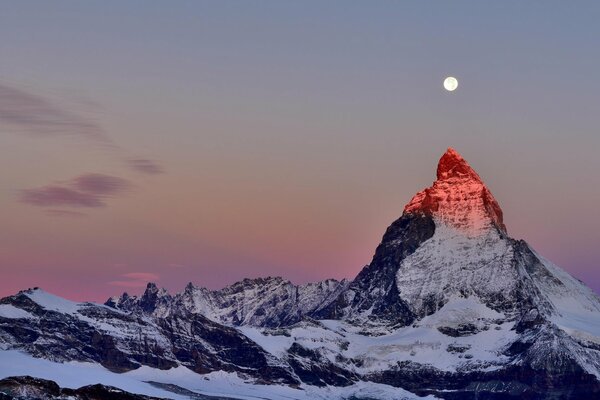 Sommet des Alpes sur fond de ciel crépusculaire. Lune au-dessus du sommet